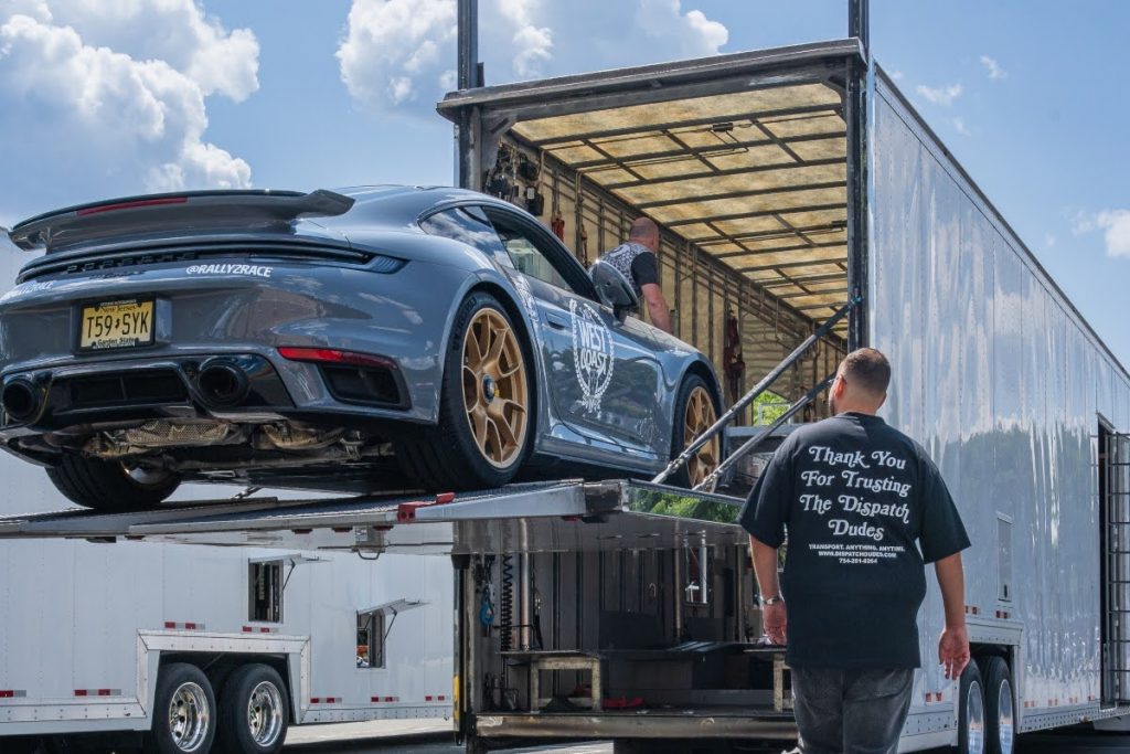 Company staff loading a vehicle onto a trailer for insured auto transport.