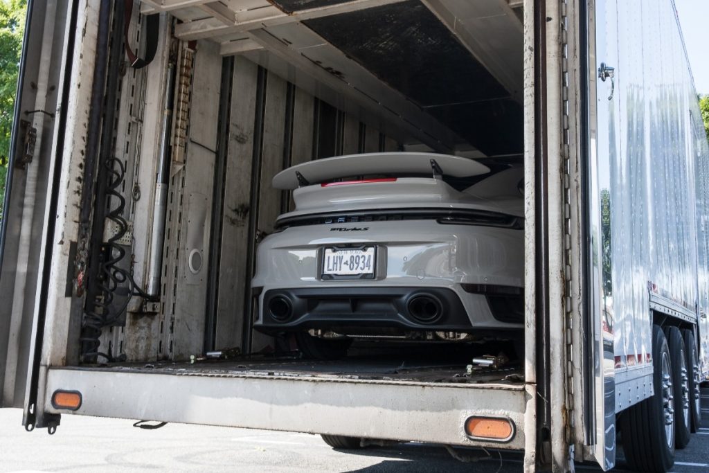 A white car in a carrier truck.
