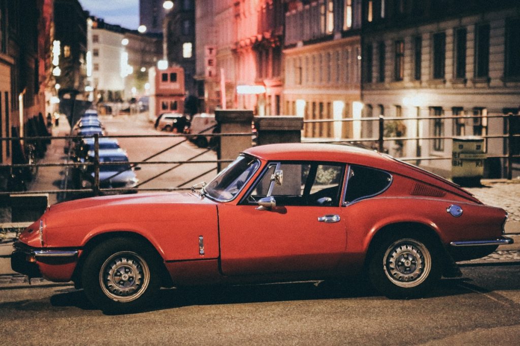 A red vintage car parked on the street.