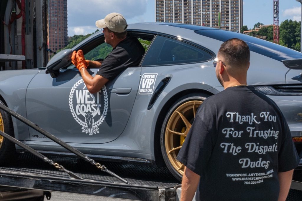 A man loading a car onto a carrier.