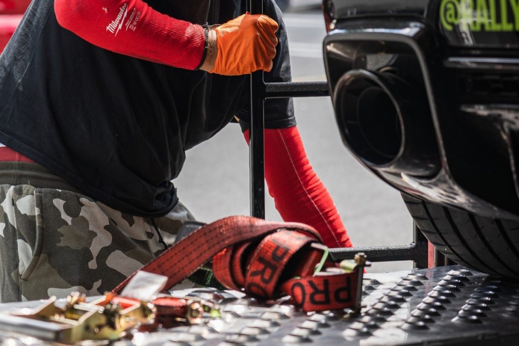 A service professional securing a car for transport.