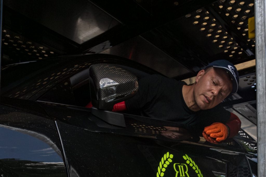 A car shipping expert loading a modified car into an enclosed carrier.
