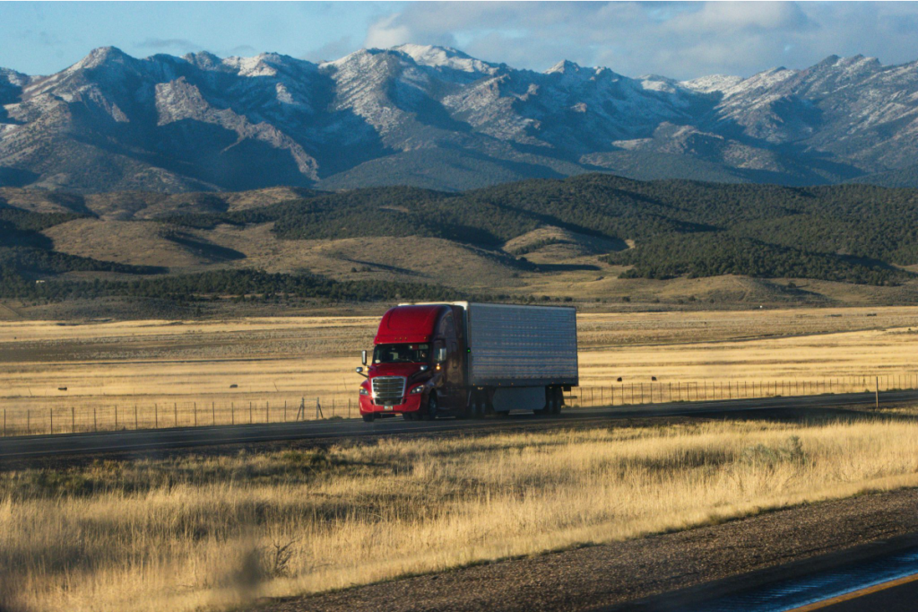 A truck transporting a car through mountains.