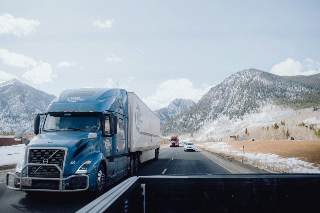 A truck transporting cars over mountains in the winter.