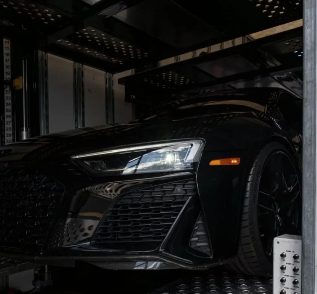 Black Audi inside an enclosed transport trailer.