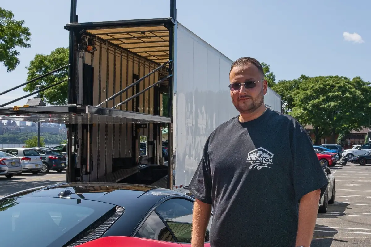 Car transport specialist standing beside an enclosed trailer.