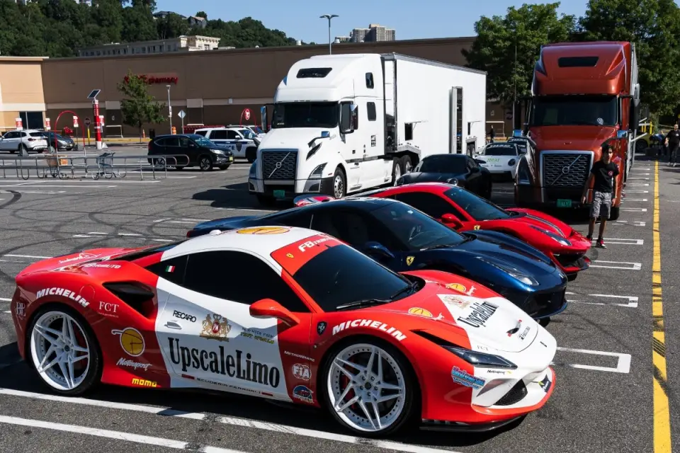 Ferrari sports cars parked near enclosed transport trucks.