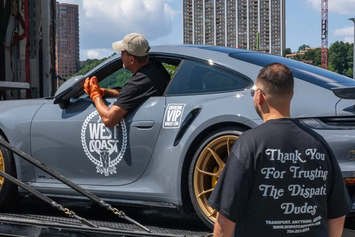 Gray Porsche being loaded while a transport specialist guides the process.