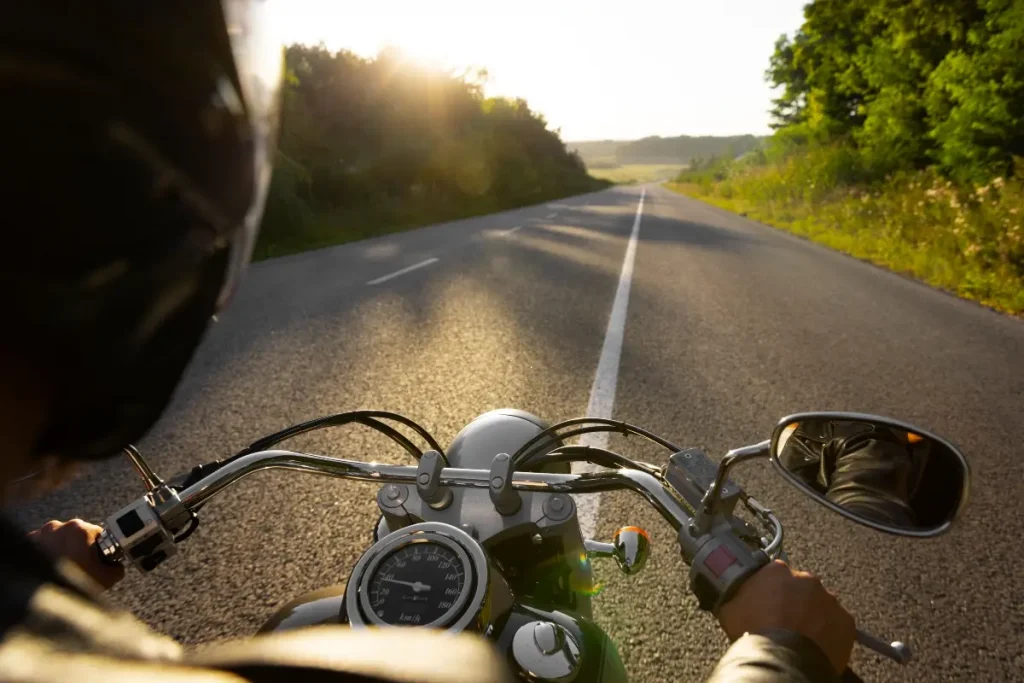 Motorcyclist riding along a sunlit open road.