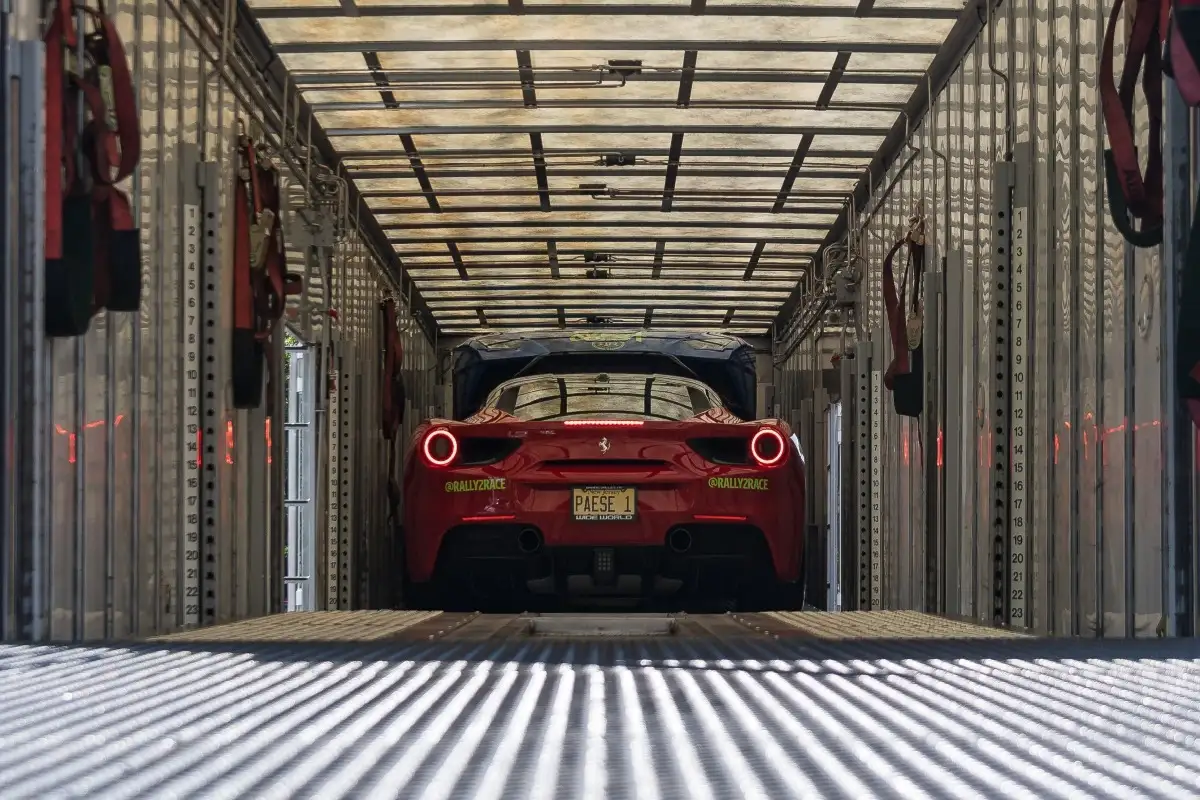 Red Ferrari secured inside an enclosed transport trailer.