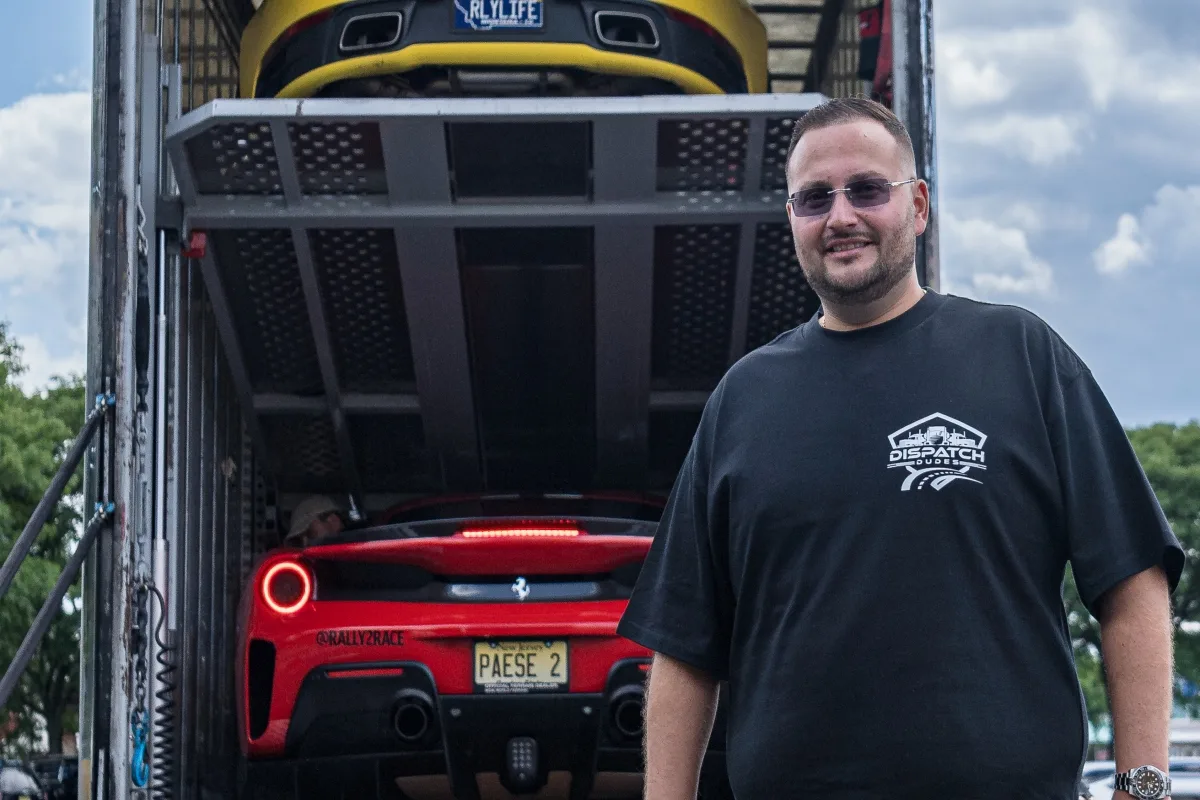 Person standing beside a red Ferrari loaded into an enclosed transport trailer.