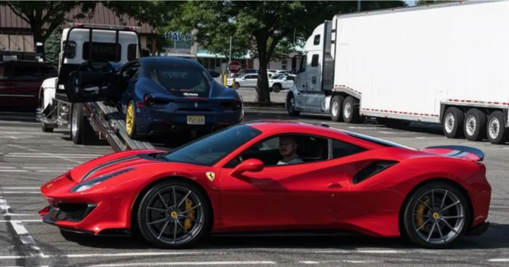 Red Ferrari parked beside a vehicle transport trailer.