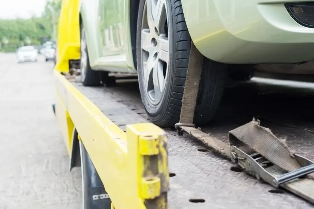 Vehicle secured with a ratchet strap on a flatbed carrier.