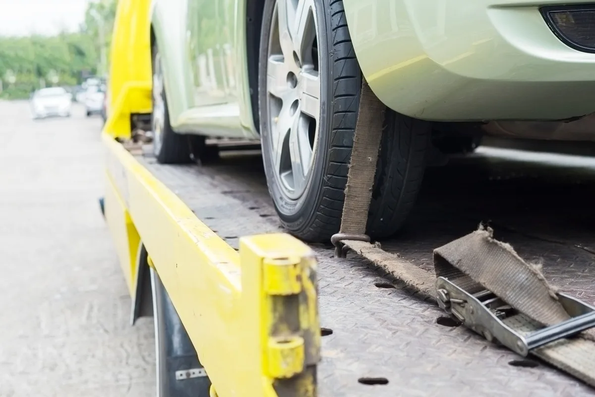 Vehicle secured with a strap on a flatbed trailer.