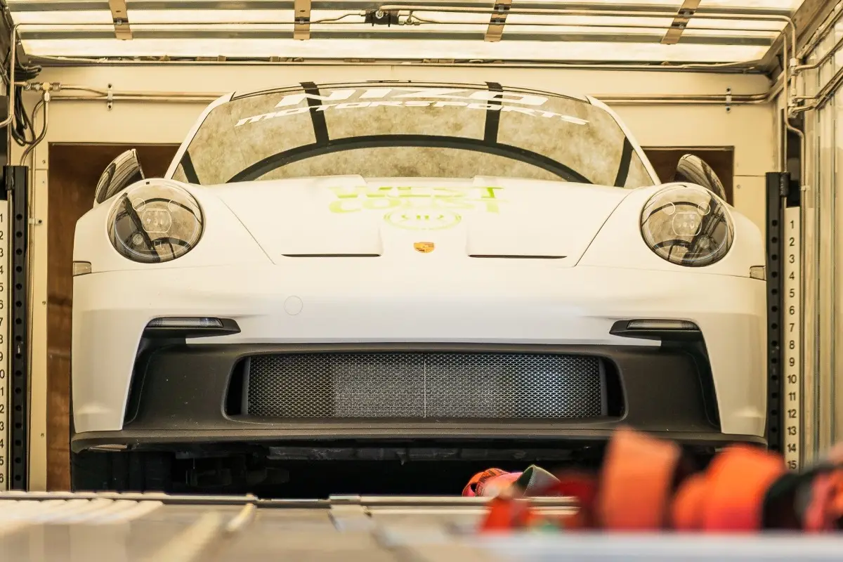 White Porsche secured inside an enclosed transport trailer.