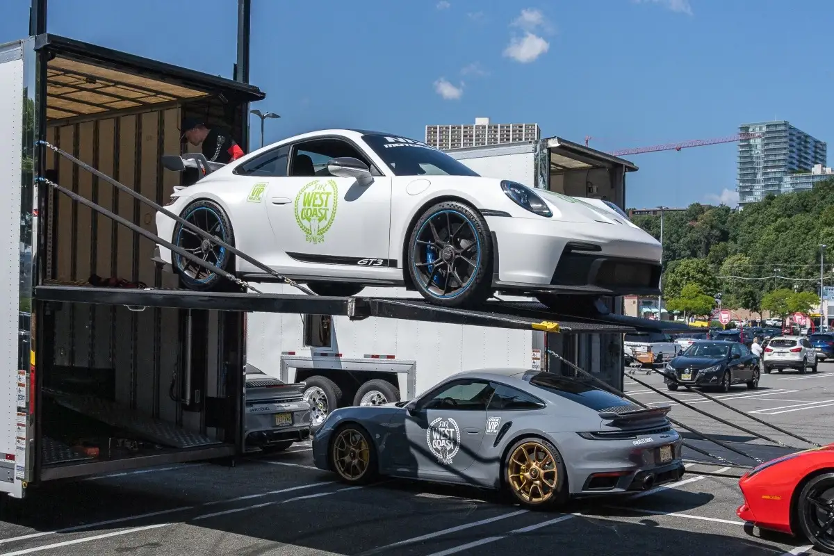 White Porsche secured on an open transport carrier.