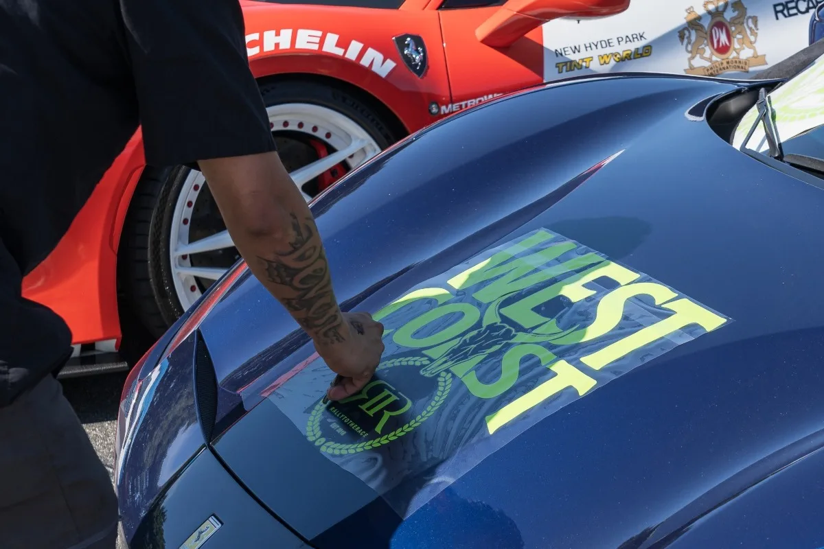Worker prepares a Ferrari for transport with protective covering.