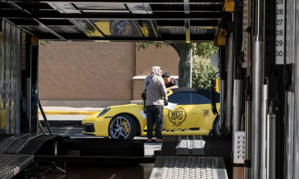 Yellow sports car being loaded into an enclosed transport trailer.