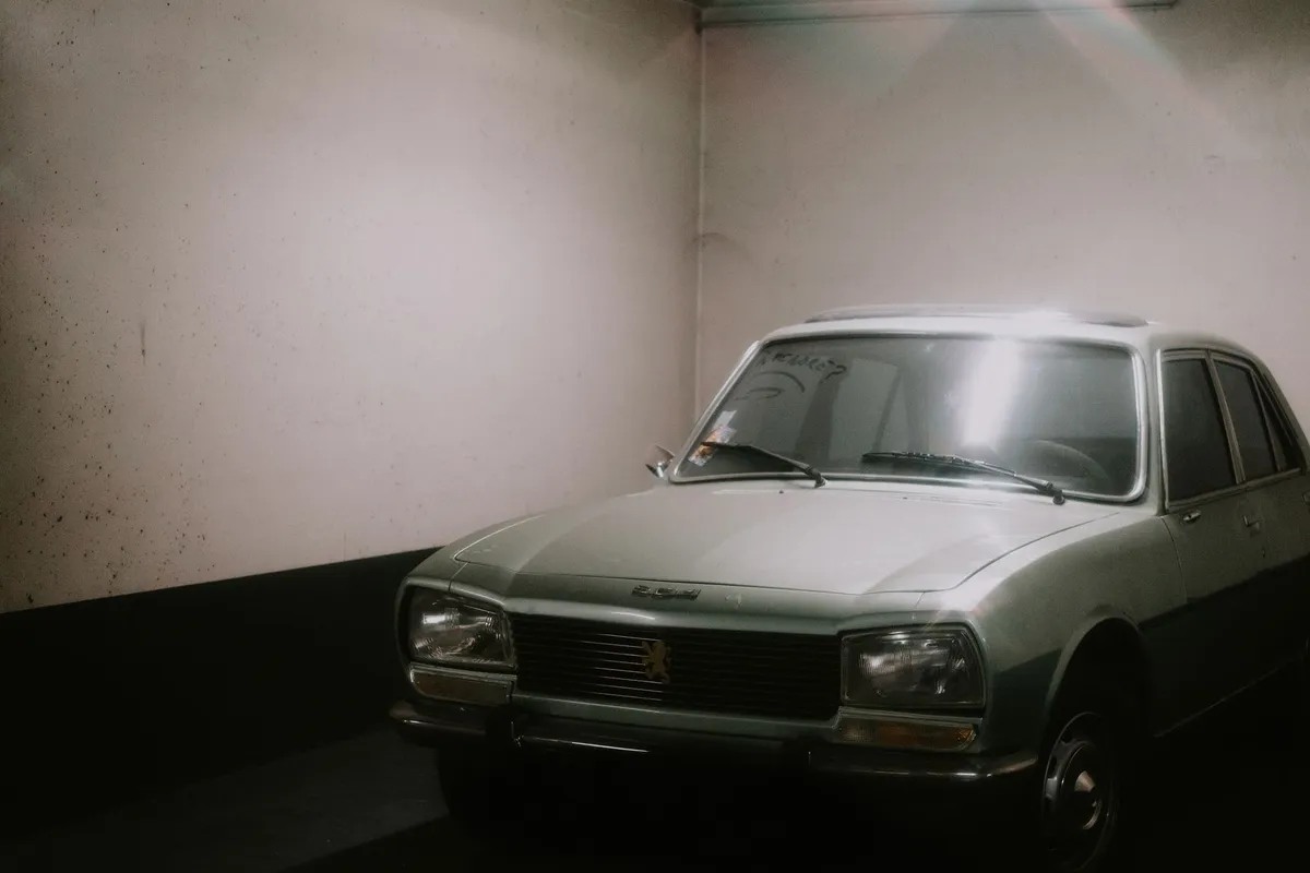 A classic retro car parked in a dimly lit garage, evoking nostalgia for auto transport choices.