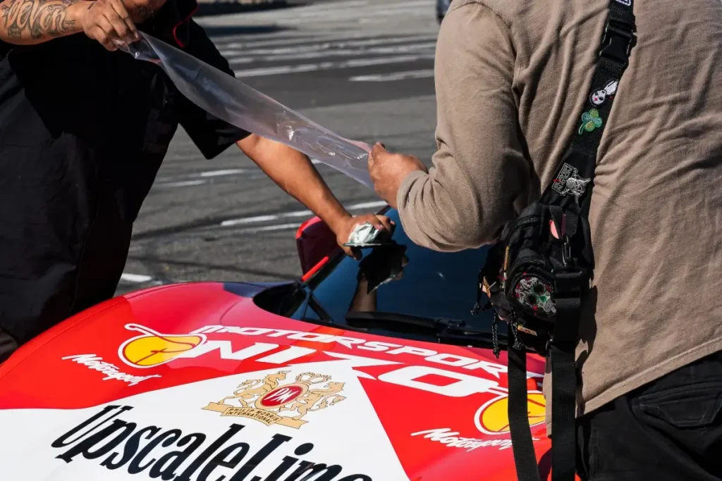 A person applying protective film to a sports car.