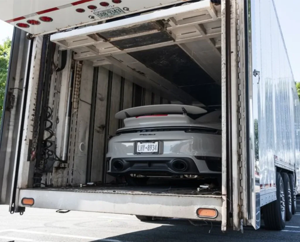 The rear of a gray sports car inside a trailer.