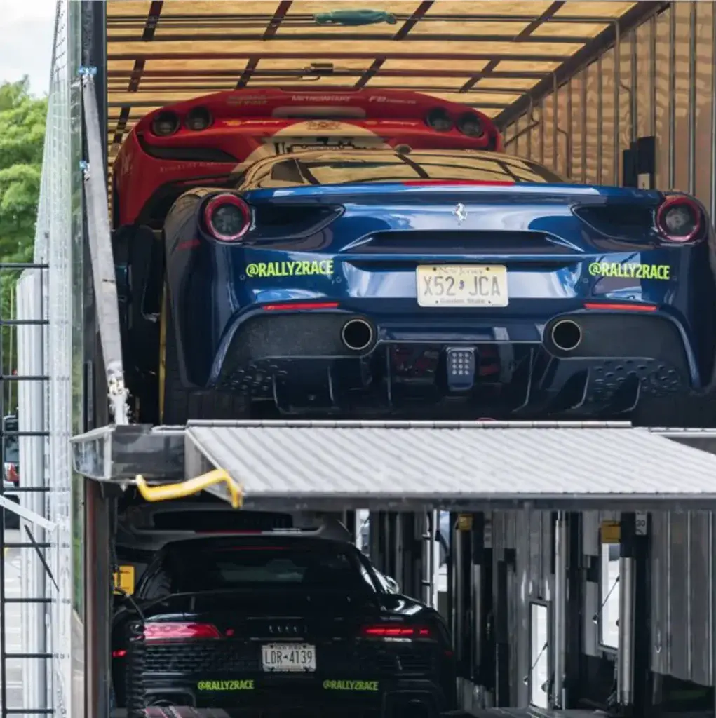 Sports cars stacked inside an enclosed carrier.