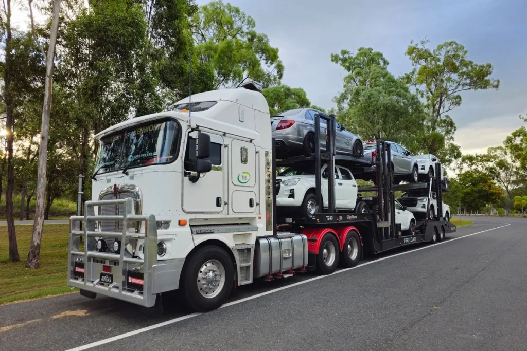 A large car carrier truck transports vehicles on a road, illustrating vehicle transport logistics.