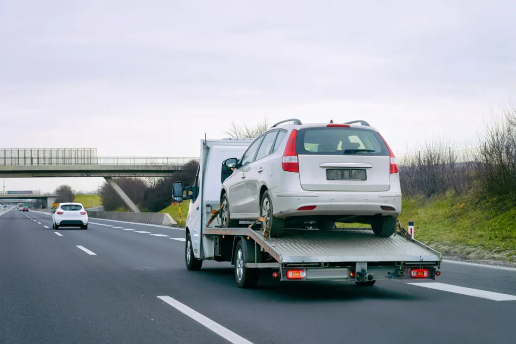 A tow truck transporting a car on a highway, illustrating vehicle transport methods.