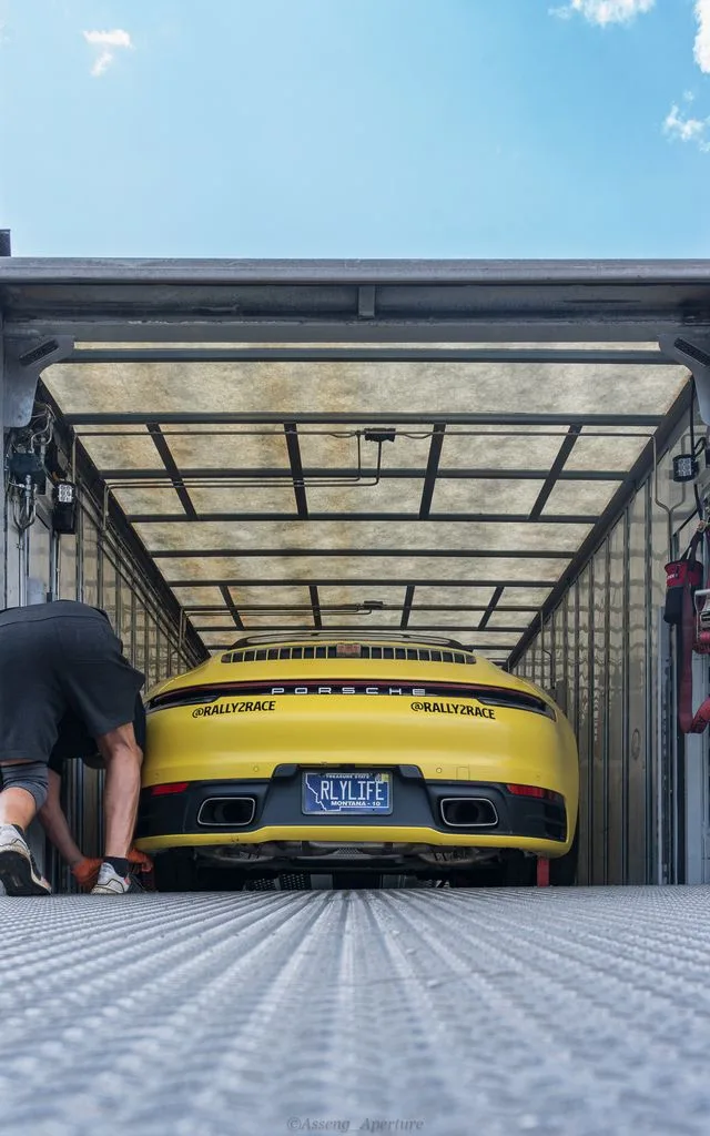 A yellow sports car inside an enclosed trailer.